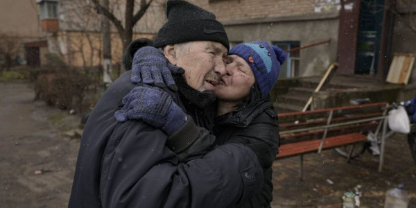 Kobieta całuje mężczyznę podczas gotowania na ogniu w pobliżu domu w Buczy. Od czasu rosyjskiej inwazji nie było tu wody, gazu i elektryczności. Kwiecień 2022. Fot. Vadym Chirda / war.ukraine