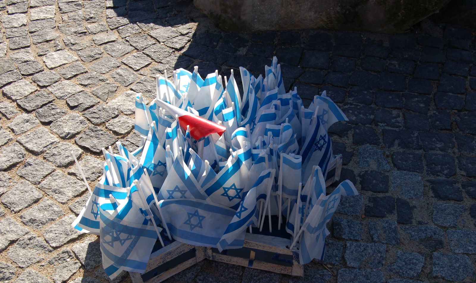 Liczne proporce - flagi Izraela i flaga Polski pośród nich - całość  na drewnianym świeczniku w kształcie gwiazdy Dawida